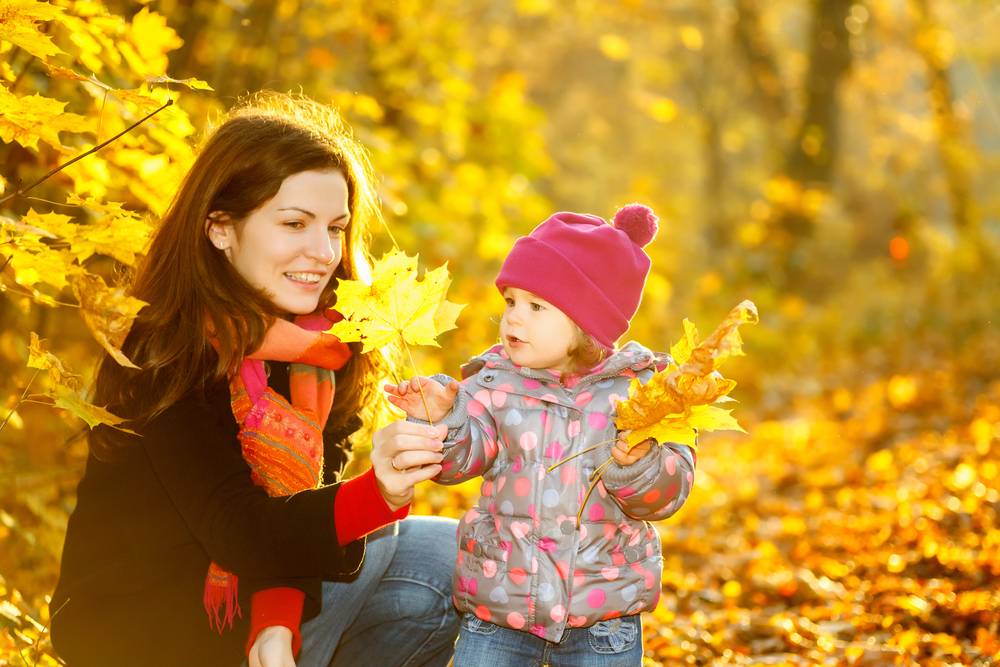 madre e hija pequeña recolectando hojas en otoño