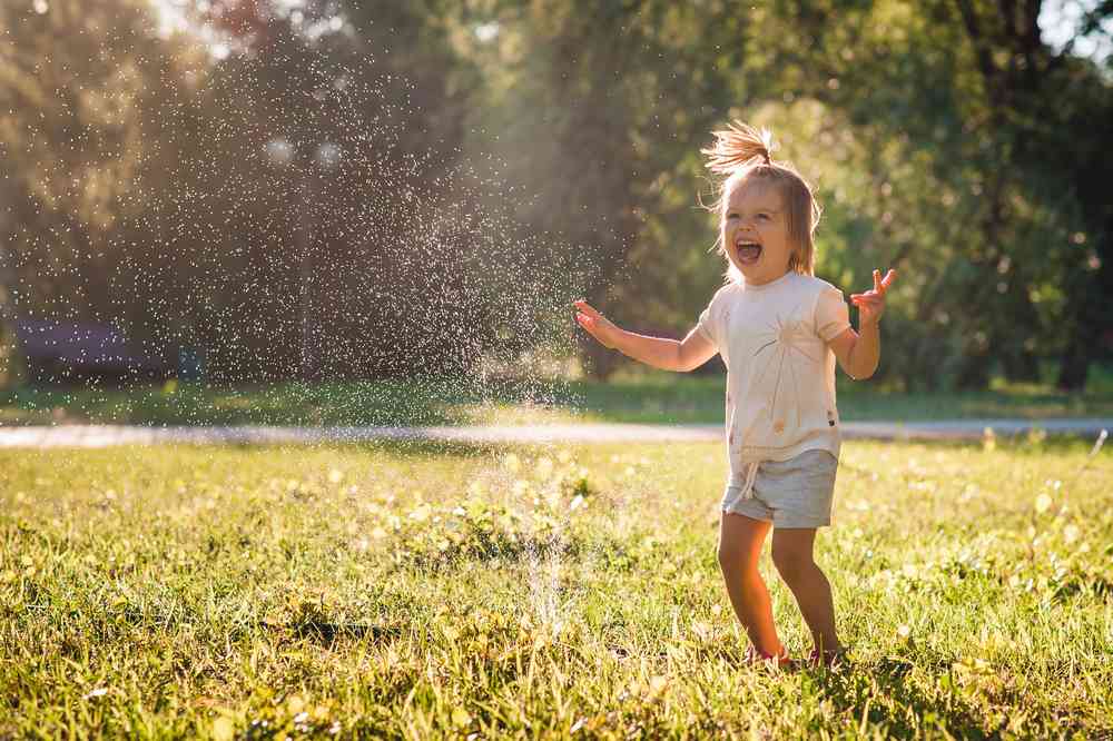 niña feliz riéndose y jugando con agua