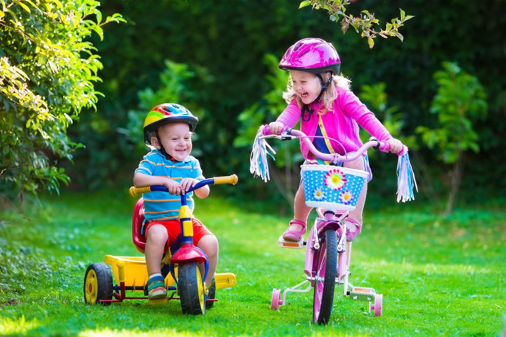 dos hermanitos andando en bicicleta y triciclo