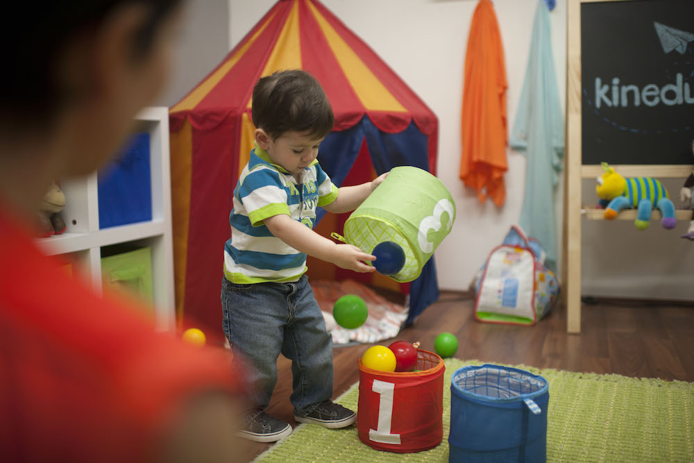 niño pequeño jugando solo con pelotas