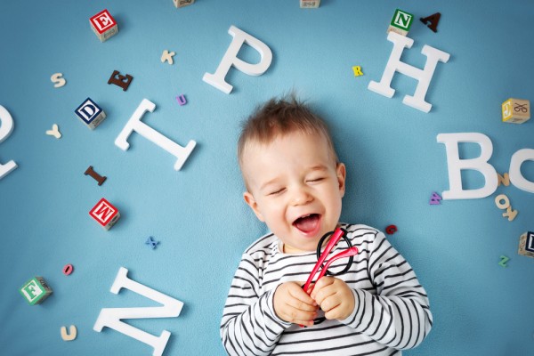 bebé pequeño riéndose rodeado de letras