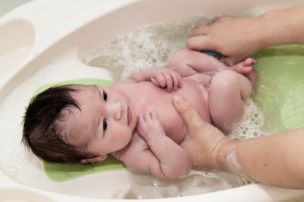 adulto bañando a un bebé recién nacido