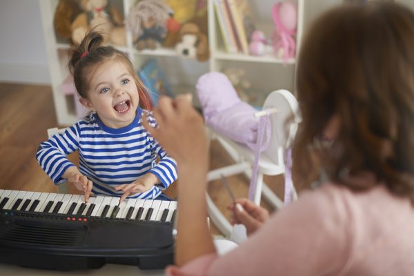 niña pequeña jugando con un piano de juguete