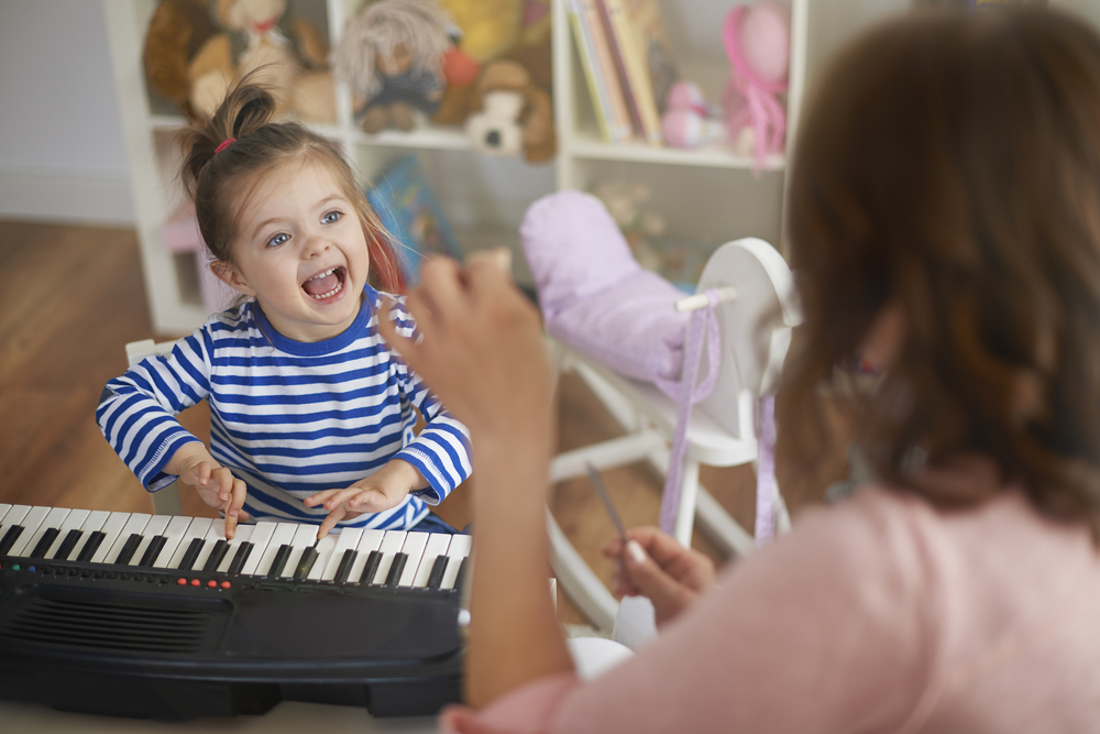 niña pequeña jugando con un piano de juguete