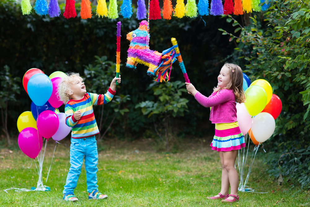dos niños rompiendo una piñata en una fiesta de cumpleaños