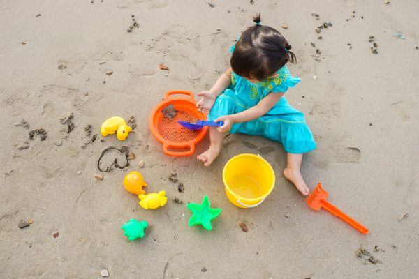 niña pequeña jugando con juguetes en la arena