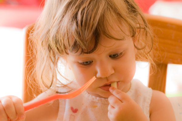 niña pequeña comiendo con un tenedor