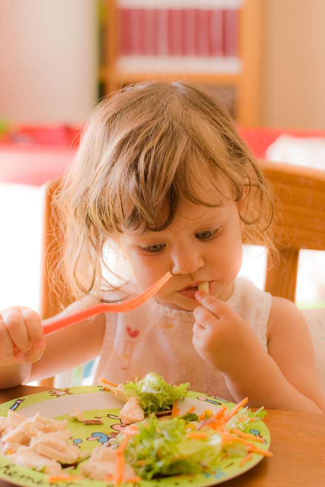 niña pequeña comiendo con un tenedor