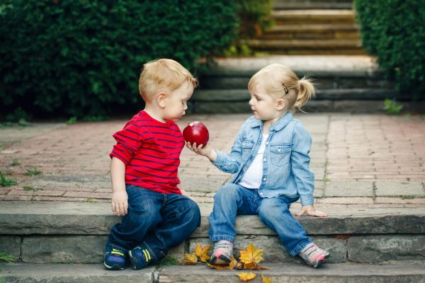 dos niños pequeños compartiendo una manzana