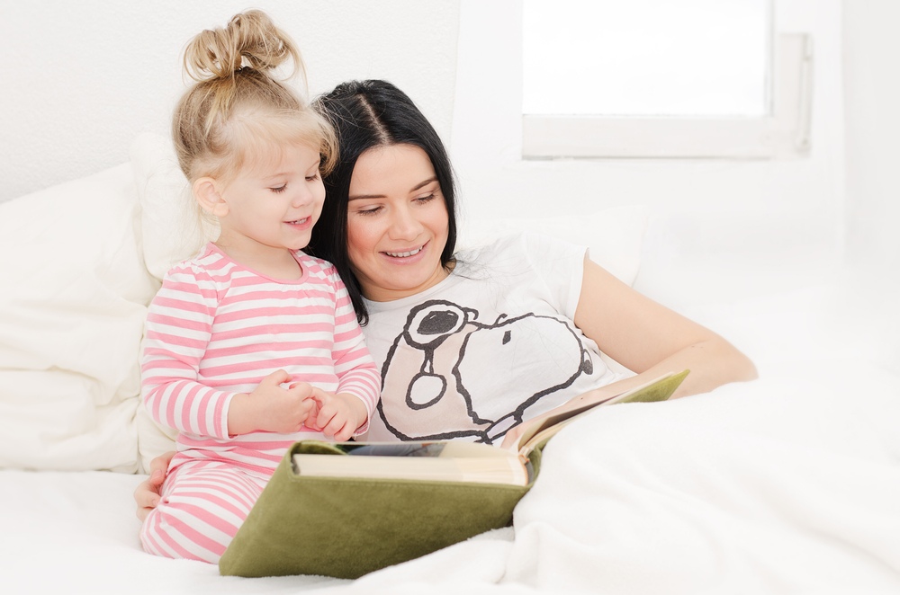 niña pequeña leyendo un libro con su mamá