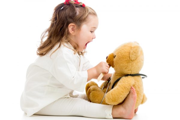 niña pequeña jugando al doctor con un oso de peluche