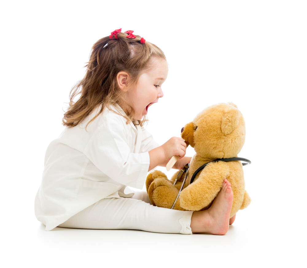 niña pequeña jugando al doctor con un oso de peluche
