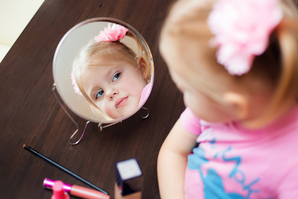 niña pequeña observa su reflejo en un espejo
