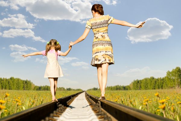 madre e hija caminando sobre las vías del tren