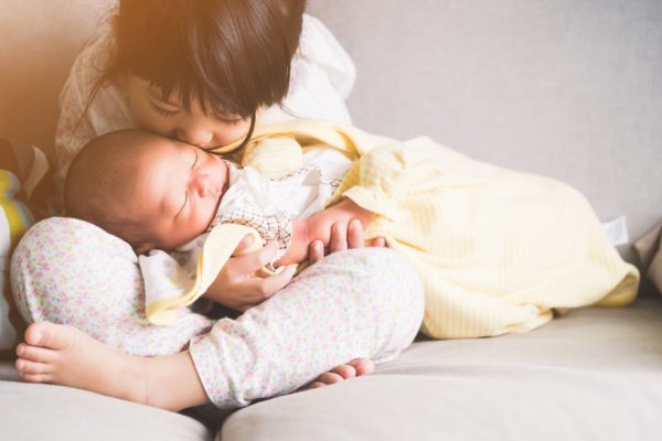 niña pequeña dándole un beso a su hermanito recién nacido