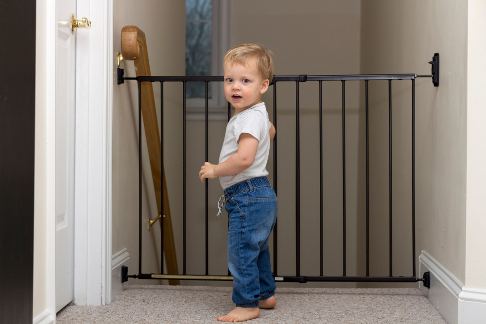 niño pequeño parado junto a una puerta de seguridad en las escaleras