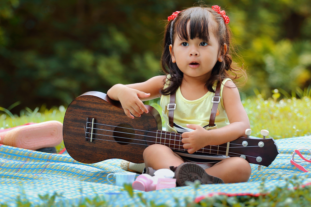 niña pequeña sosteniendo una guitarra de juguete