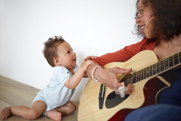 bebé viendo a su madre tocar la guitarra