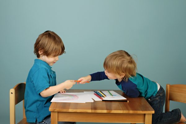 dos niños compartiendo crayones