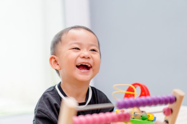niño pequeño sonriendo y jugando con un ábaco