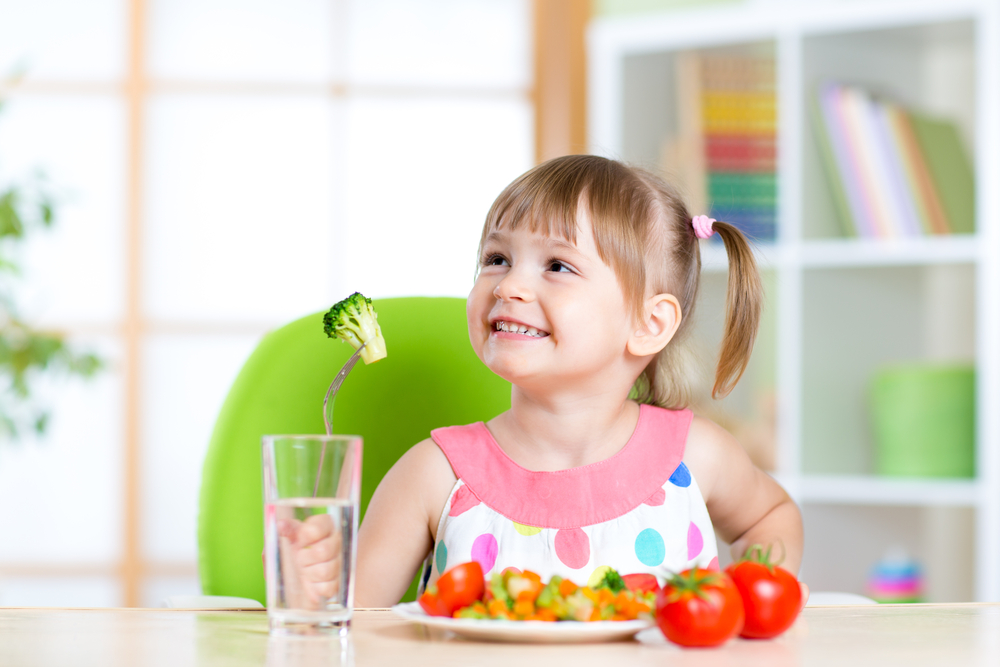 niña pequeña comiendo verduras por su cuenta