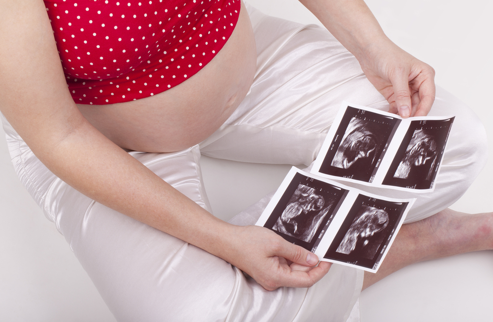 mujer embarazada mirando dos ultrasonidos